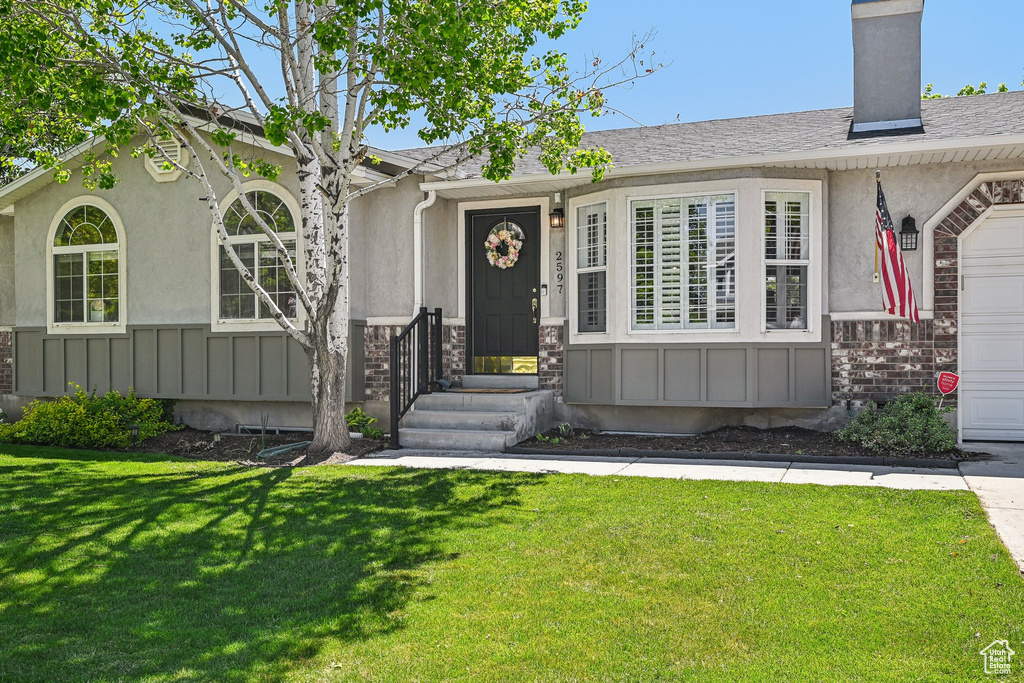 View of front of home featuring a front yard, a garage, stucco siding, and board and batten siding