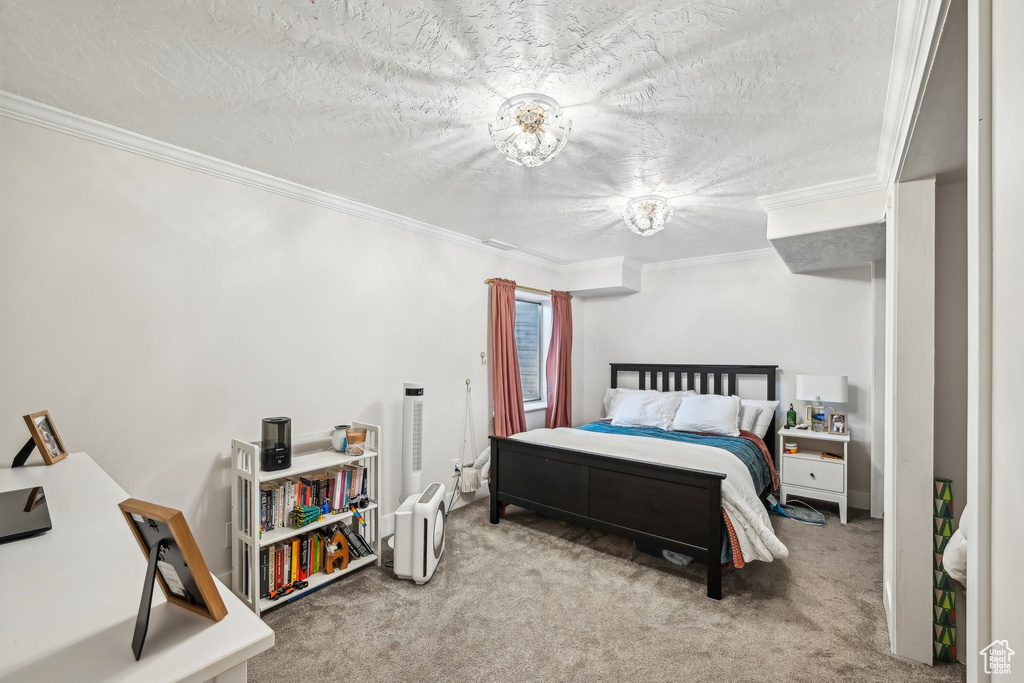 Carpeted bedroom featuring ornamental molding and a textured ceiling