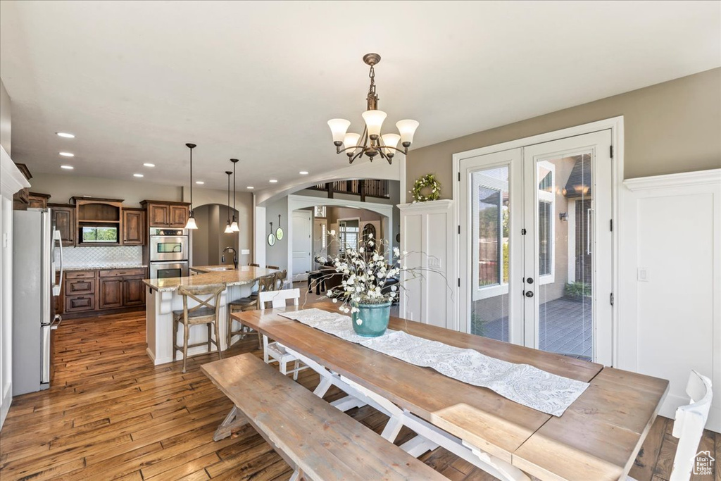 Dining room featuring arched walkways, recessed lighting, light wood-style floors, french doors, and a chandelier