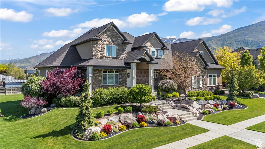 Craftsman-style house with stone siding, a mountain view, and a front lawn