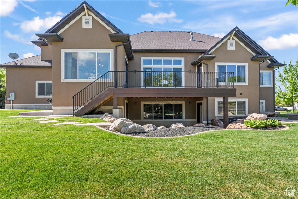 Back of house with stucco siding, a yard, stairway, and a wooden deck