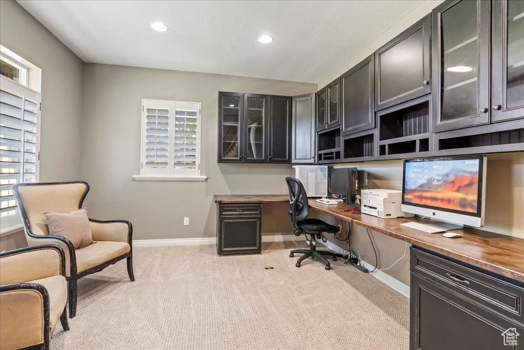 Office space with built in desk, recessed lighting, light carpet, and baseboards