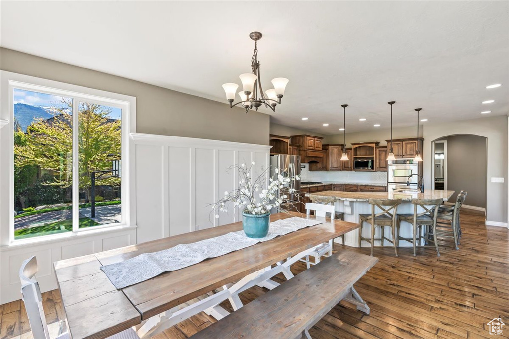 Dining space featuring arched walkways, recessed lighting, a chandelier, and dark wood-style flooring
