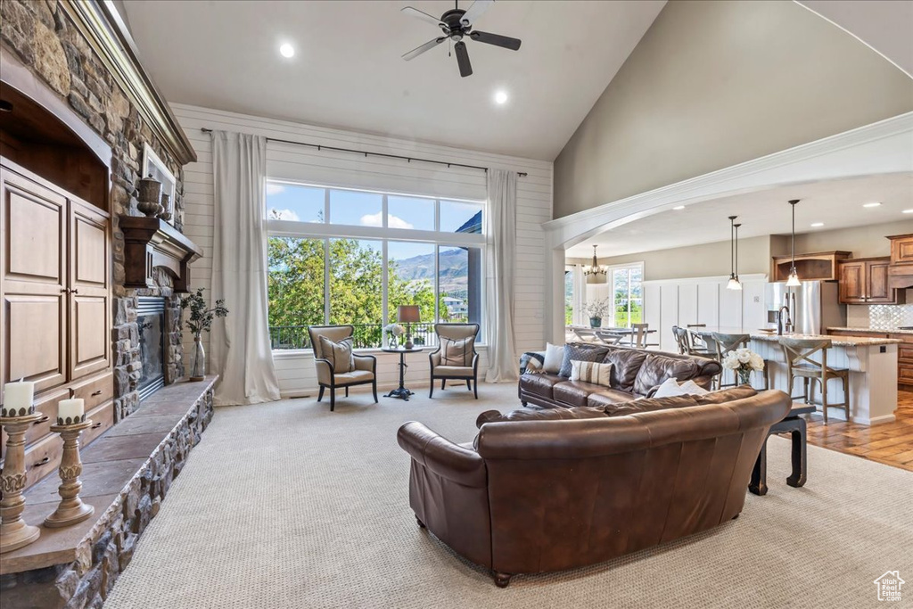 Living room featuring arched walkways, high vaulted ceiling, a stone fireplace, ceiling fan, and recessed lighting