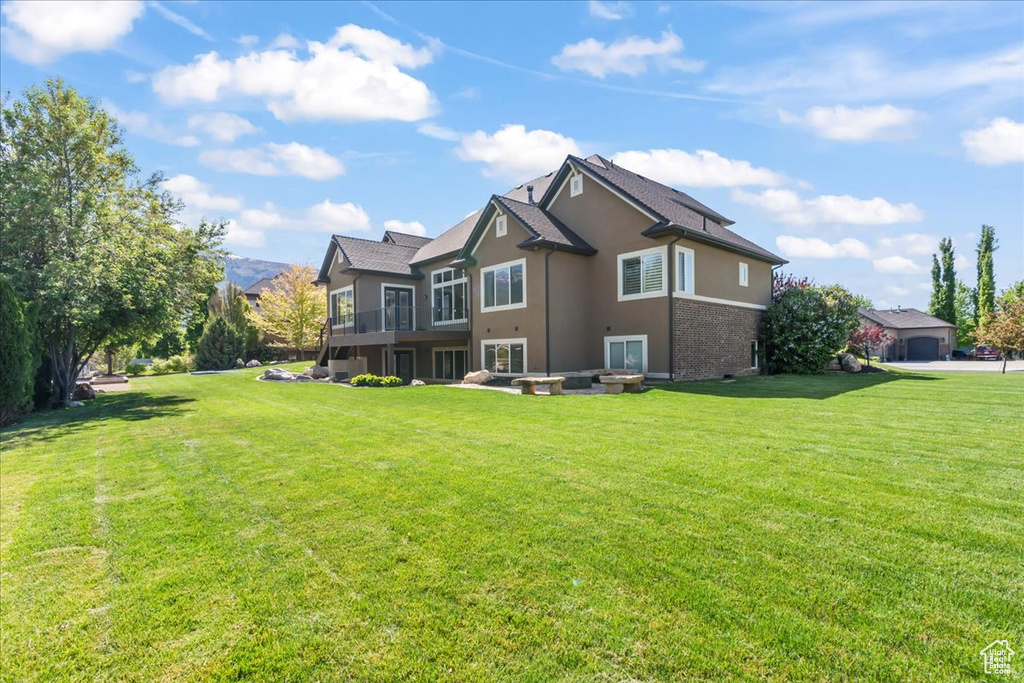 Rear view of property featuring a lawn and stucco siding