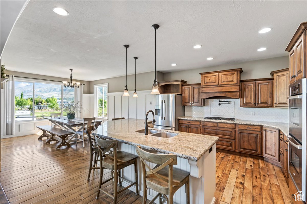 Kitchen with a sink, appliances with stainless steel finishes, light wood-style floors, brown cabinets, and recessed lighting