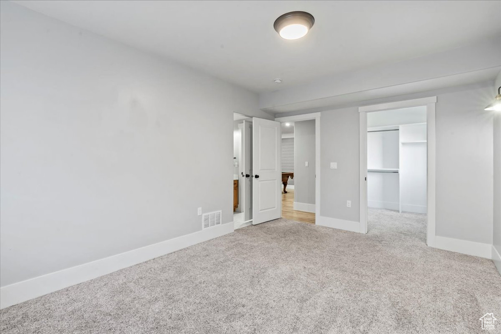 Unfurnished bedroom with light carpet, baseboards, a closet, and a walk in closet