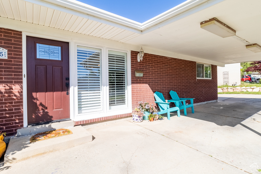 View of exterior entry featuring brick siding and a patio area