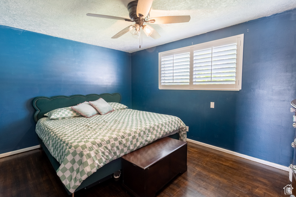 Bedroom with wood finished floors, a textured ceiling, baseboards, and ceiling fan