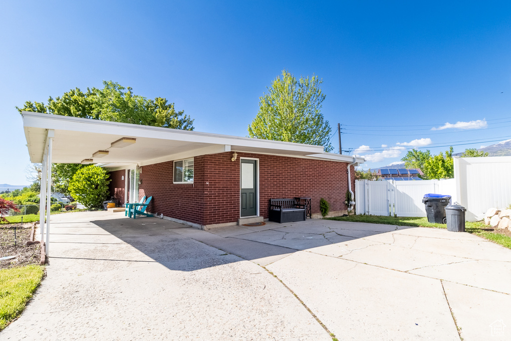 Back of house featuring concrete driveway, brick siding, a gate, and fence