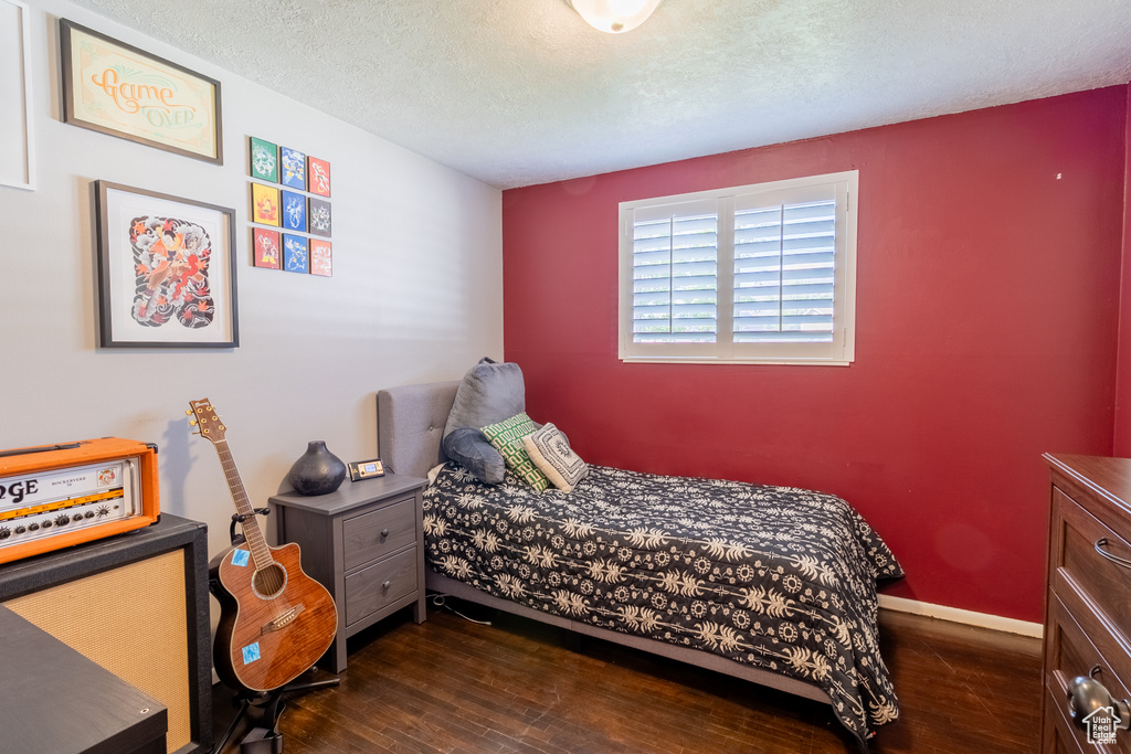 Bedroom with dark wood-style floors, a textured ceiling, and baseboards