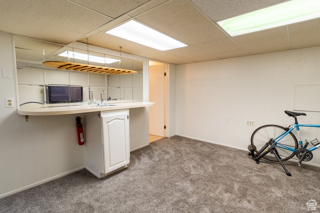 Kitchen with a sink, carpet floors, a drop ceiling, light countertops, and baseboards