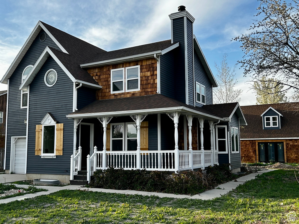 View of front of house featuring covered porch, roof with shingles, and a chimney