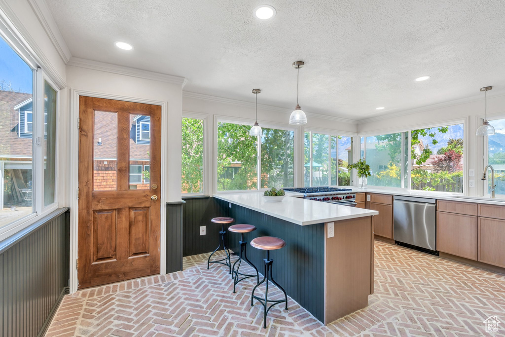 Kitchen featuring dishwasher, brick floors, a sink, a textured ceiling, and light countertops