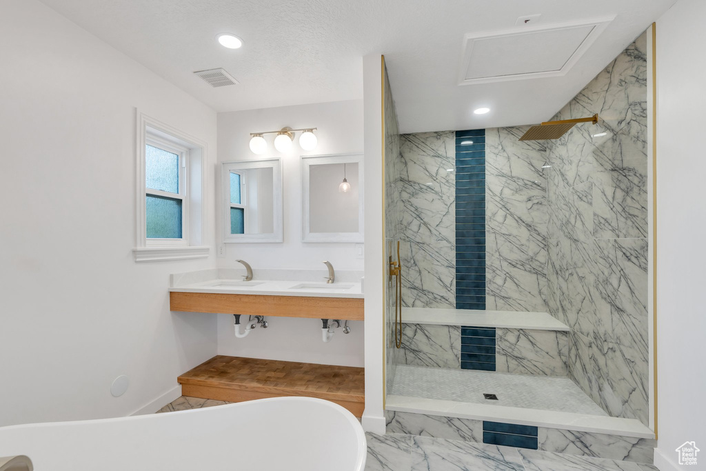 Bathroom featuring a freestanding bath, a marble finish shower, marble look tile flooring, and recessed lighting