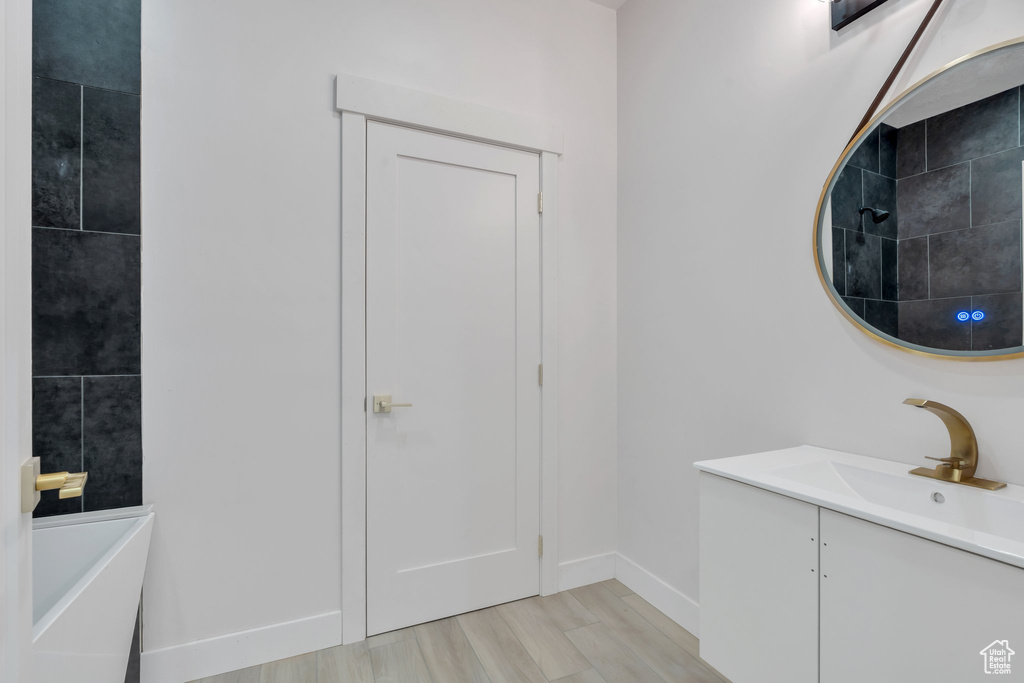 Full bathroom with a bath, vanity, tiled shower, and baseboards