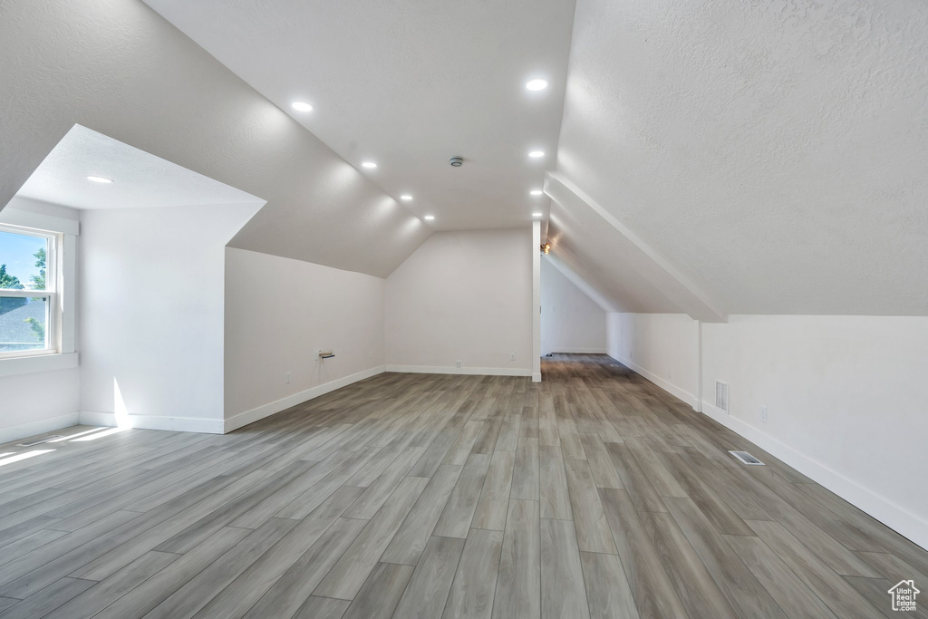 Additional living space with light wood-style floors, recessed lighting, baseboards, and lofted ceiling