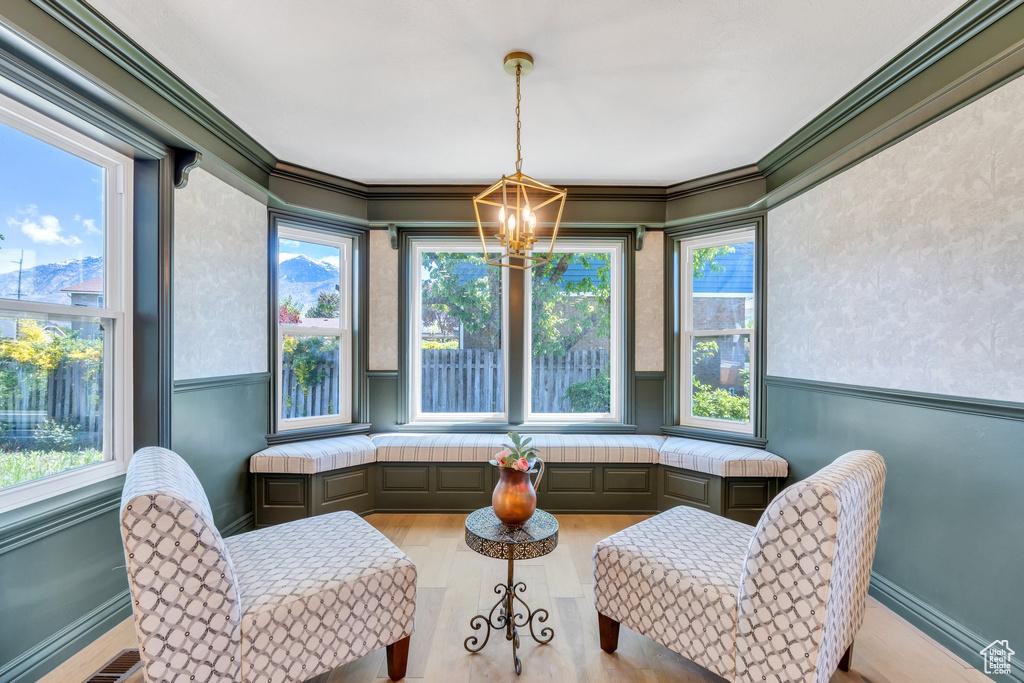 Living area featuring a chandelier, wood finished floors, plenty of natural light, and ornamental molding