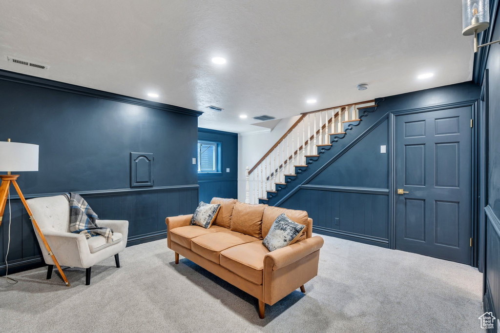 Carpeted living room featuring stairs, recessed lighting, and ornamental molding