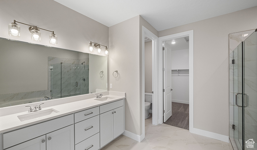 Full bathroom with marble look tiles, a stall shower, baseboards, toilet, and double vanity