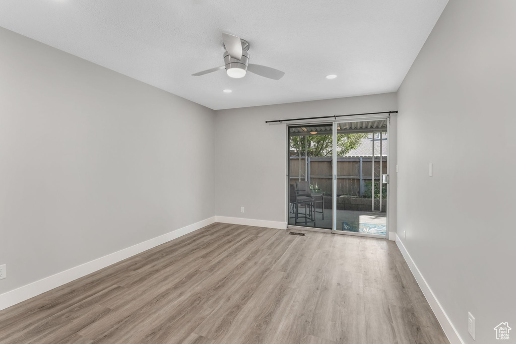 Empty room with wood finished floors, a ceiling fan, baseboards, and recessed lighting
