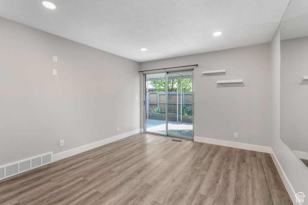 Empty room featuring wood finished floors, baseboards, recessed lighting, and a textured ceiling
