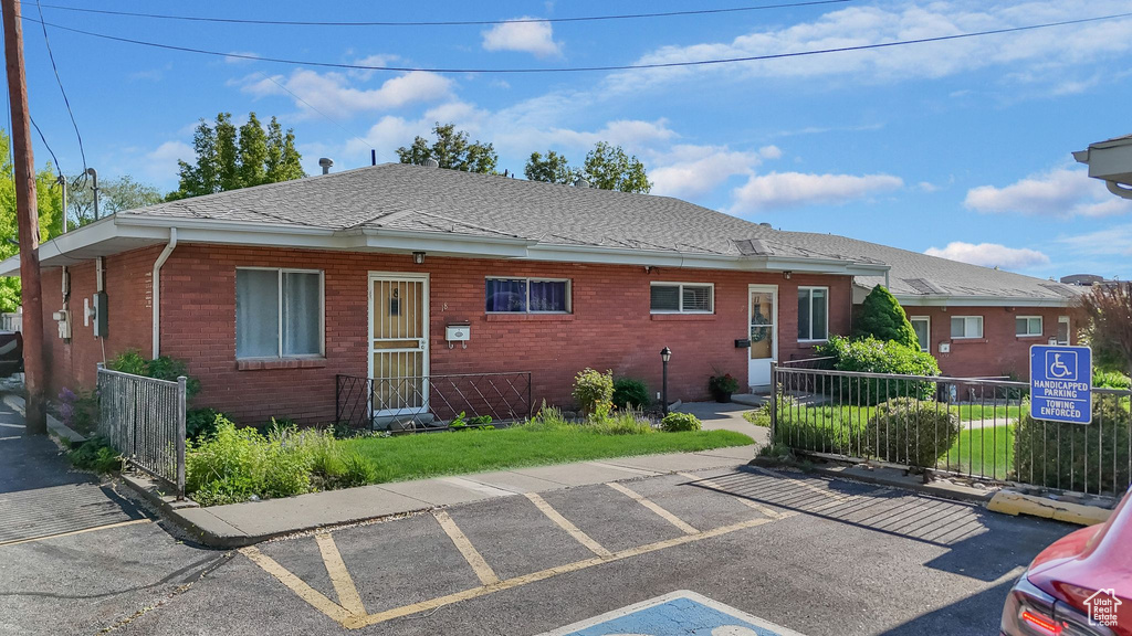 View of front of house with brick siding, fence, and a shingled roof