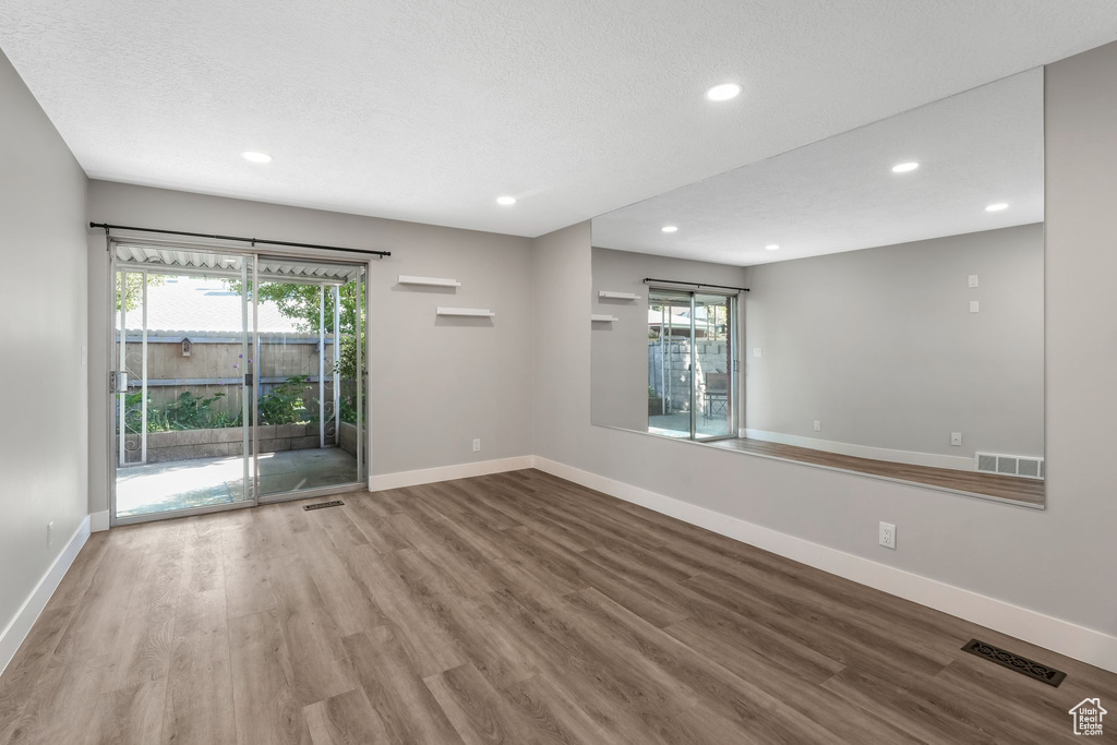 Spare room featuring wood finished floors, recessed lighting, baseboards, and plenty of natural light