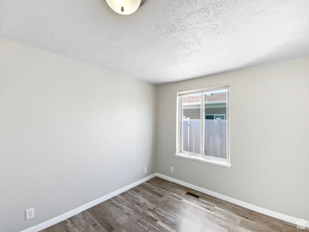 Spare room with wood finished floors, baseboards, and a textured ceiling