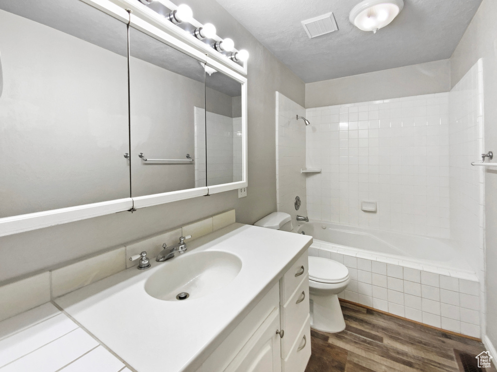 Full bathroom featuring wood finished floors, toilet, tiled shower / bath, and vanity