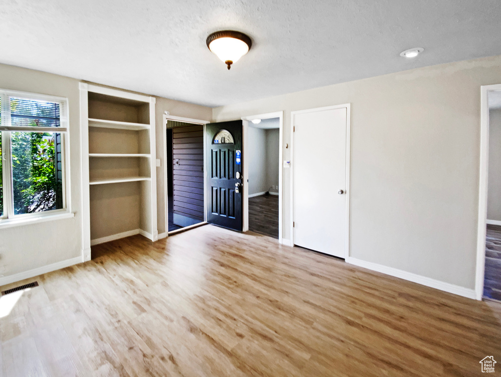 Unfurnished bedroom featuring two closets, baseboards, wood finished floors, and a textured ceiling