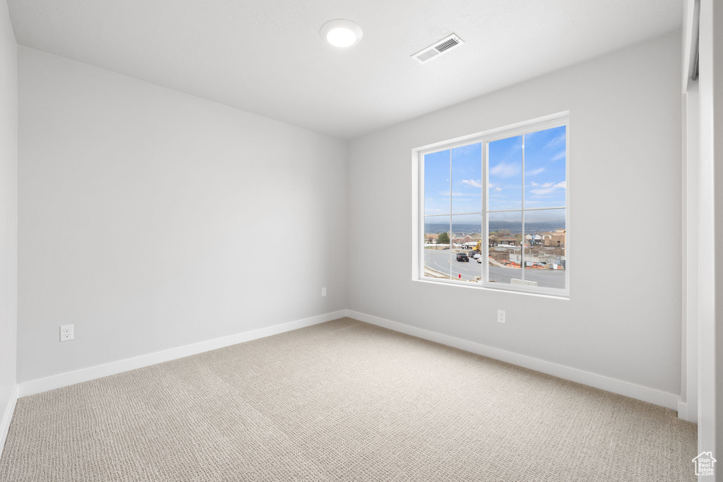 Carpeted spare room featuring baseboards