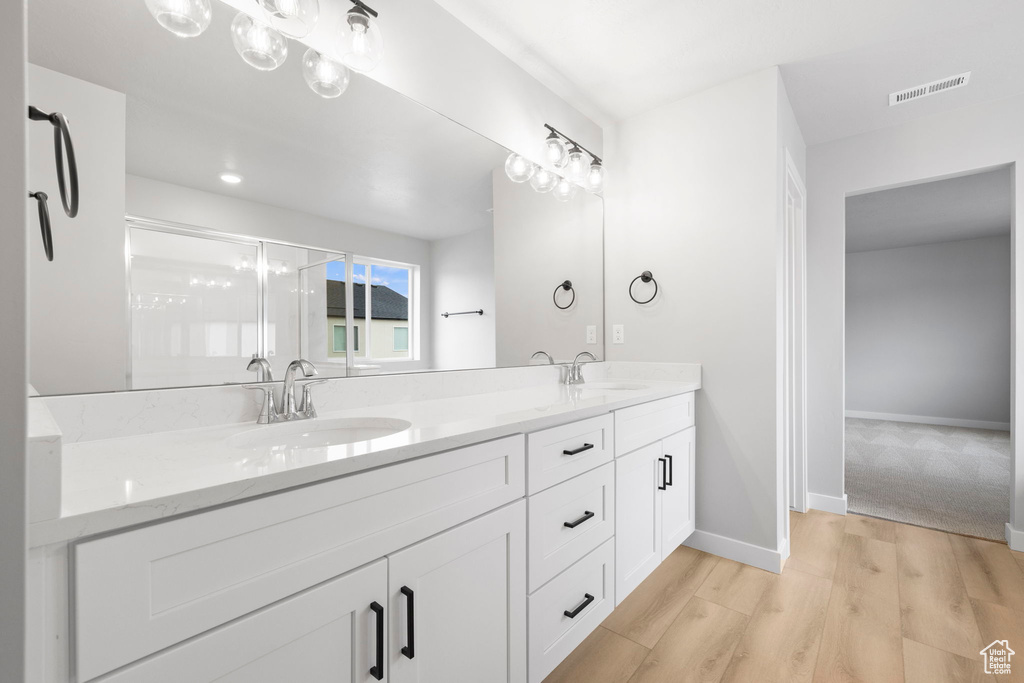 Full bath featuring double vanity, wood finished floors, and baseboards