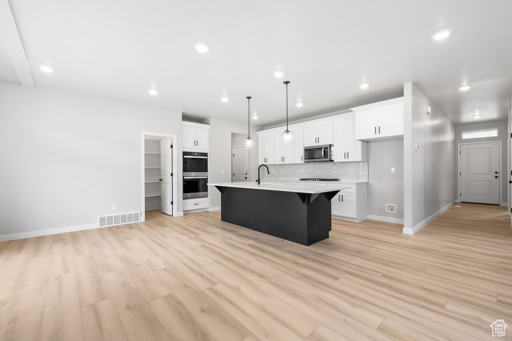 Kitchen featuring appliances with stainless steel finishes, a sink, light countertops, recessed lighting, and baseboards