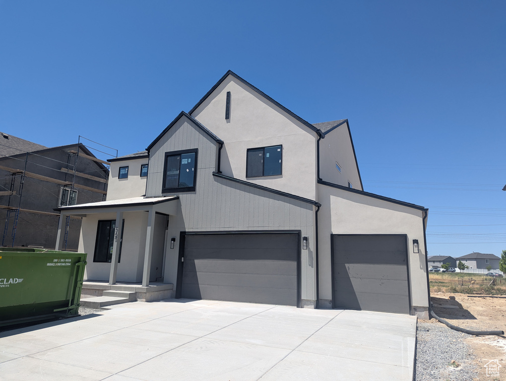 View of front of house with concrete driveway, an attached garage, and stucco siding