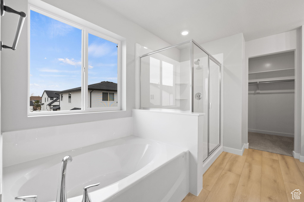 Full bathroom featuring a stall shower, a bath, a walk in closet, wood finished floors, and recessed lighting