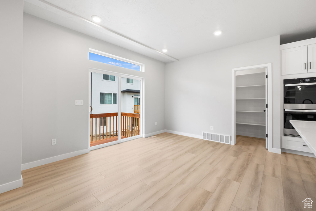 Unfurnished living room with light wood-type flooring, recessed lighting, and baseboards