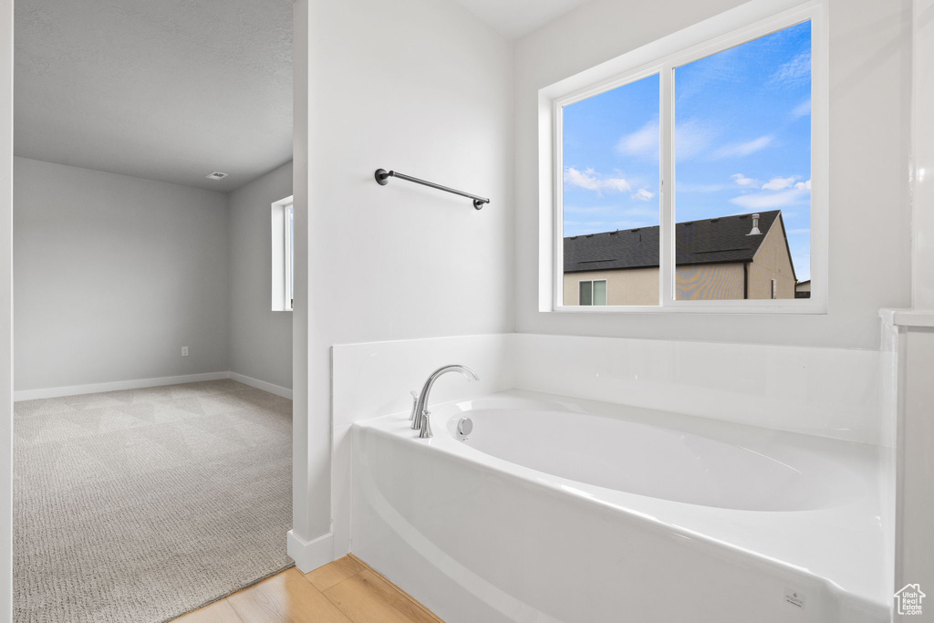 Bathroom featuring a bath and baseboards