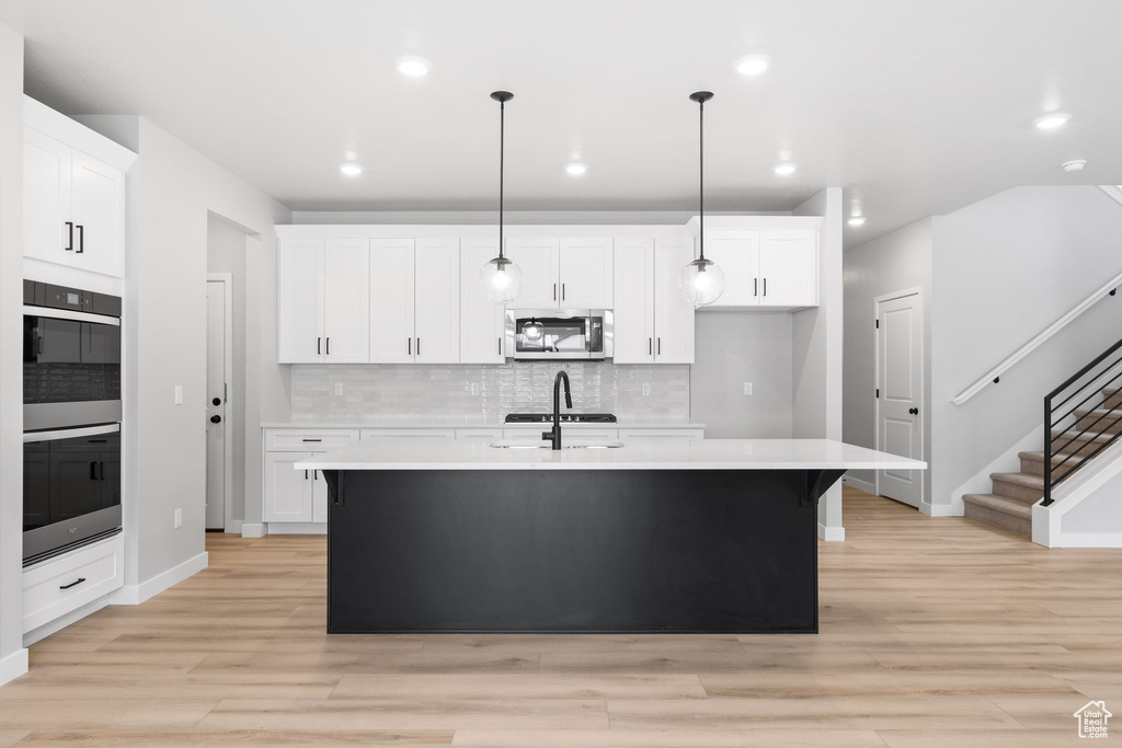 Kitchen with stainless steel microwave, light countertops, decorative backsplash, baseboards, and recessed lighting