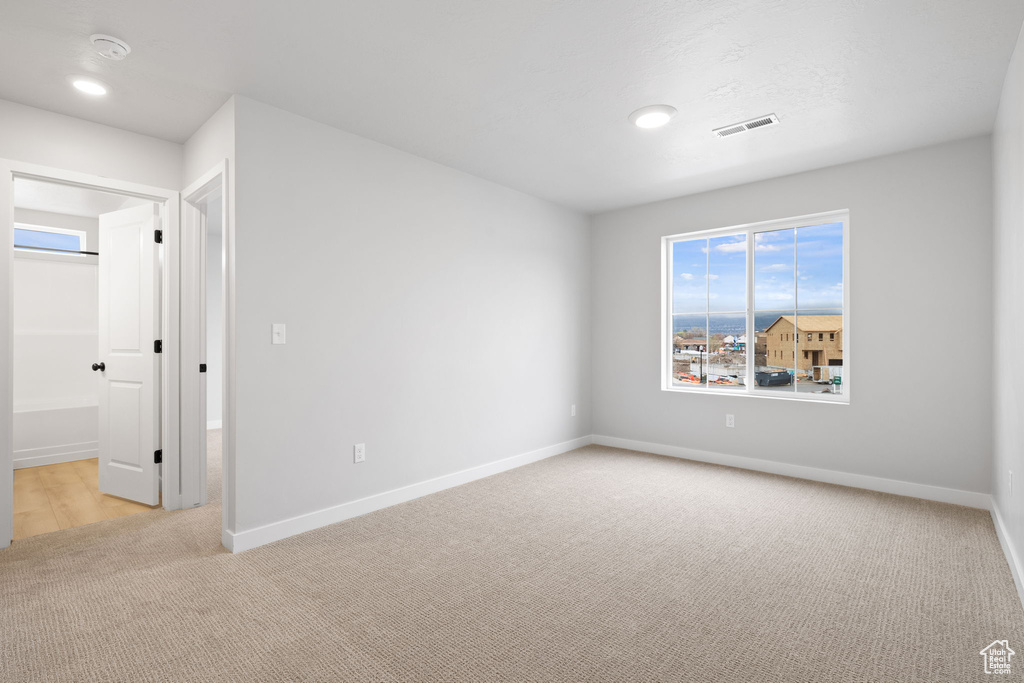 Spare room with light carpet, baseboards, and recessed lighting