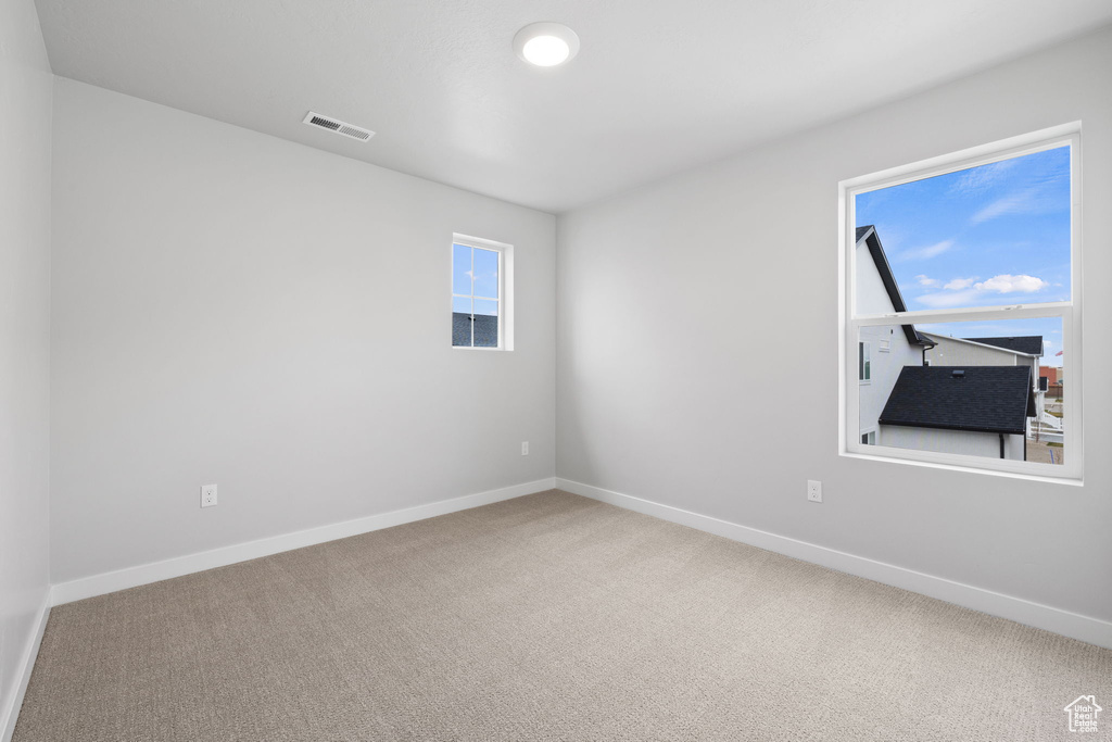 Carpeted spare room featuring baseboards