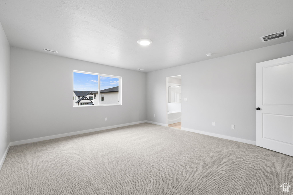 Empty room with light colored carpet and baseboards
