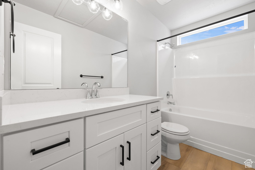 Full bath with wood finished floors, toilet, vanity, and tub / shower combination