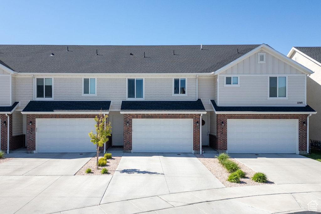 Townhome / multi-family property featuring a garage, driveway, and board and batten siding