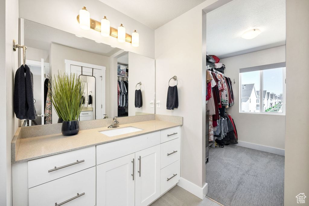 Bathroom featuring baseboards, vanity, and a walk in closet
