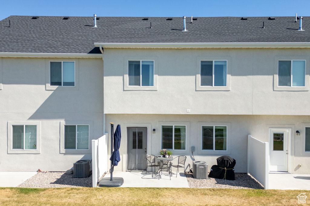 Back of house featuring roof with shingles, a patio area, stucco siding, and cooling unit
