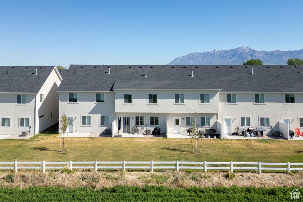 Back of property featuring a patio area, a mountain view, stucco siding, and a shingled roof