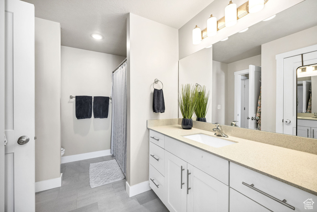 Bathroom featuring baseboards, toilet, vanity, and recessed lighting