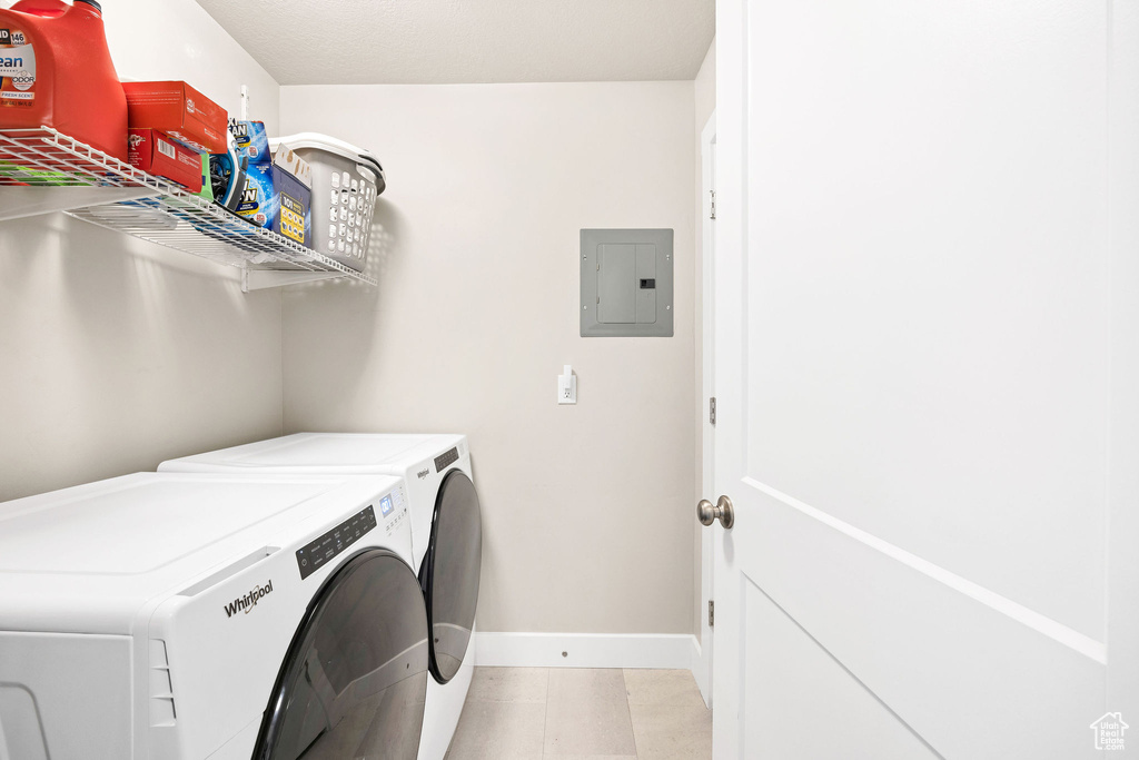 Laundry room featuring electric panel, washing machine and dryer, and baseboards
