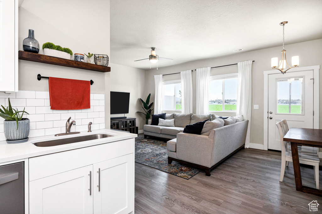 Living area featuring dark wood finished floors, a ceiling fan, a chandelier, and baseboards